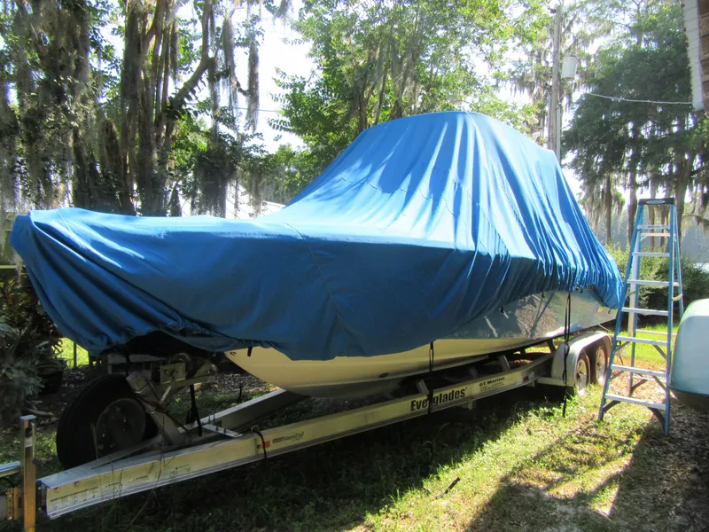 2017 Everglades 255 Center Console boat covered with blue tarp on trailer.