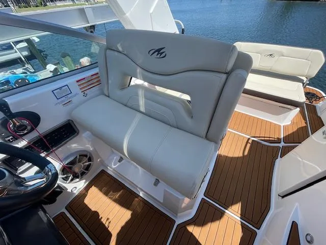 2019 Monterey 295 boat interior with white seating and wood flooring by the water.