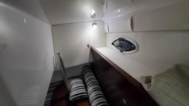 2019 Monterey 295 cabin interior with striped cushions and porthole window.