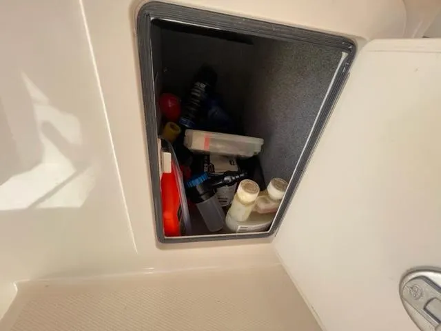 Storage compartment on a 2017 Grady-White 300 Marlin boat with various items.